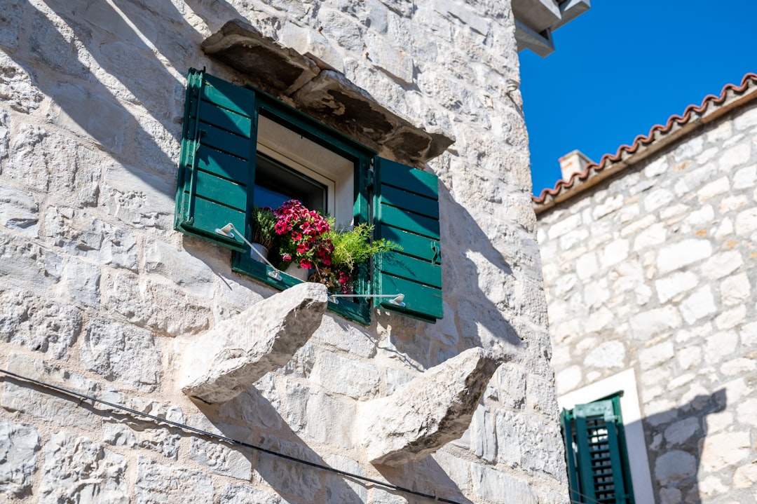 Home a-stone-building-with-green-shutters-and-a-window-5pitijbhwl4